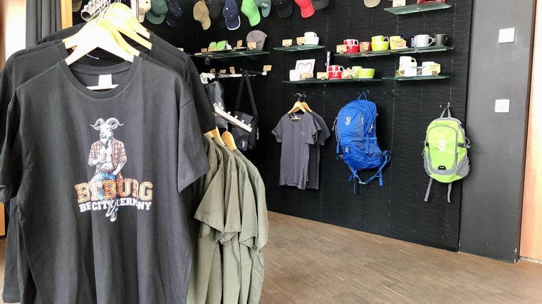 Een verkoopgebied met T-shirts, petten en rugzakken. De sfeer is modern en uitnodigend.