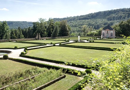 Franz&ouml;sischer Garten mit symmetrischen Hecken und Rasenfl&auml;chen, im Hintergrund ein kleines Geb&auml;ude und bewaldete H&uuml;gel unter blauem Himmel., &copy; V. Teuschler