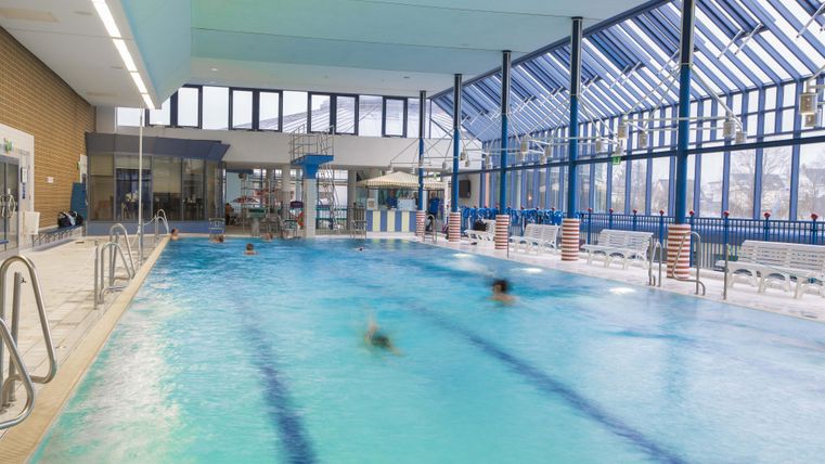 Een zwembad met helder water en moderne voorzieningen. Grote ramen laten veel licht binnen en creëren een uitnodigende sfeer.