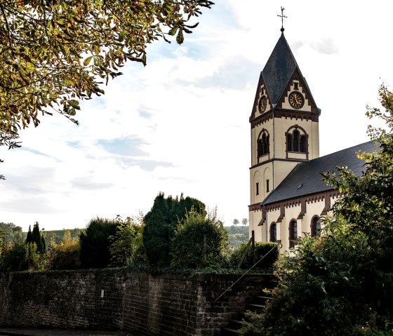 Die Kirche St. Remigius in Oberweis, umgeben von B&auml;umen und einer Steinmauer, unter einem bew&ouml;lkten Himmel., &copy; TI Bitburger Land