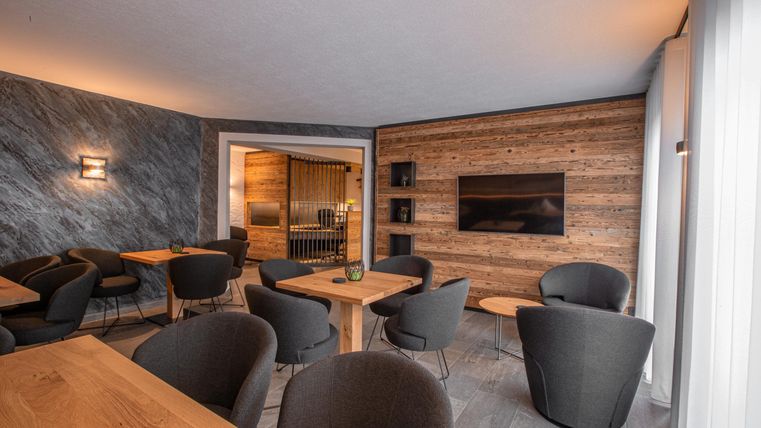 Un café moderne avec des tables et des chaises confortables. Les murs sont en bois et en pierre, créant une atmosphère accueillante.