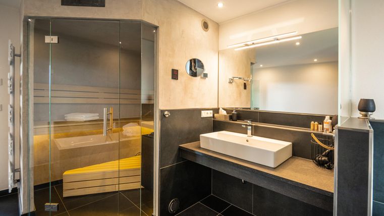 Une salle de bains moderne avec une douche en verre et un ensemble de lavabo élégant. Le design est élégant et utilise une combinaison de couleurs sombres et claires.