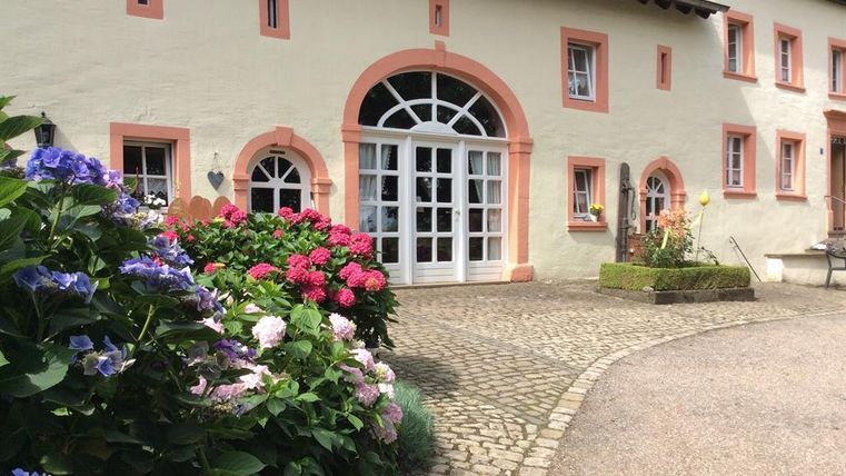 Un bâtiment charmant avec une jolie façade et de grandes fenêtres.
Des fleurs colorées embellissent l'entrée et créent une atmosphère accueillante.