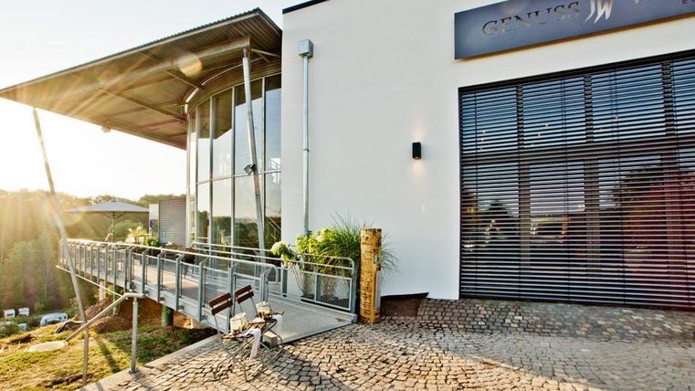 Un bâtiment moderne avec de grandes fenêtres et une véranda.
Au premier plan, il y a un vélo sur une place pavée.