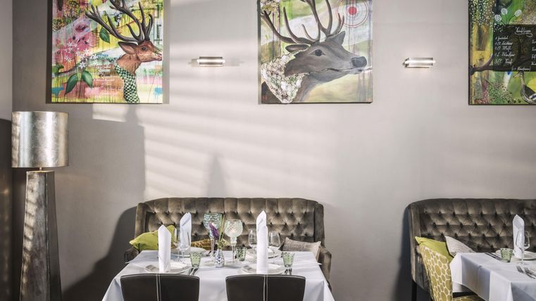 Un restaurant élégant avec des tables raffinées et des banquettes confortables. Les murs sont décorés de portraits d'animaux colorés.