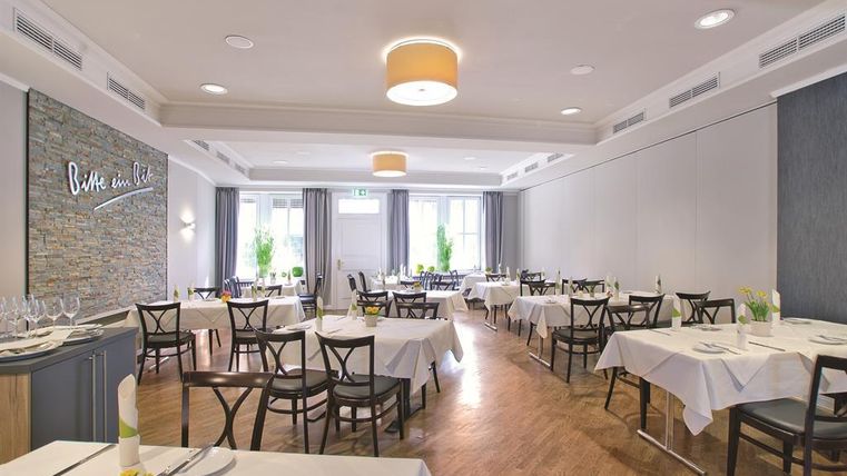 An elegant restaurant with bright tables and chairs. Large windows provide pleasant light and an inviting atmosphere.