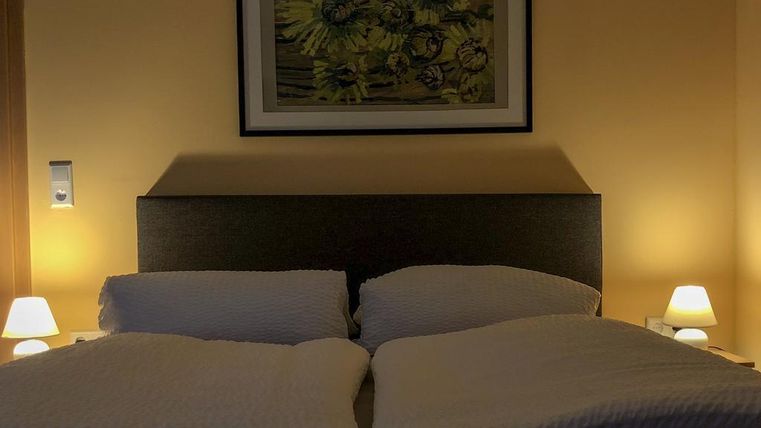 A cozy bedroom with a double bed and soft pillows. Gentle light from bedside lamps creates a relaxed atmosphere.