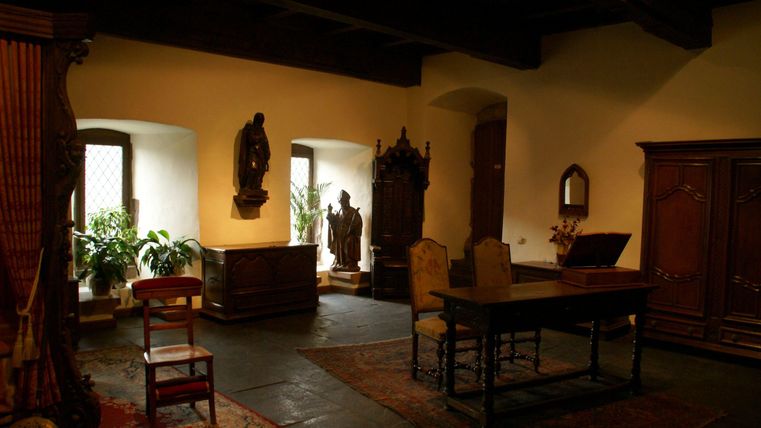 Une pièce confortable avec un plafond en bois et plusieurs fenêtres. Dans la pièce se trouvent une table, des chaises et quelques objets décoratifs.