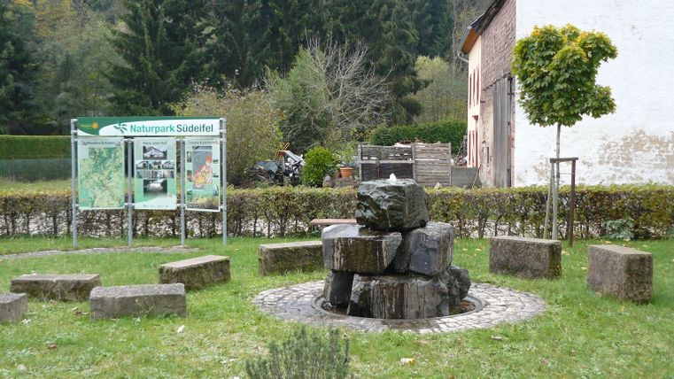 Brunnen in Mettendorf mit Infotafel des Naturparks Südeifel.