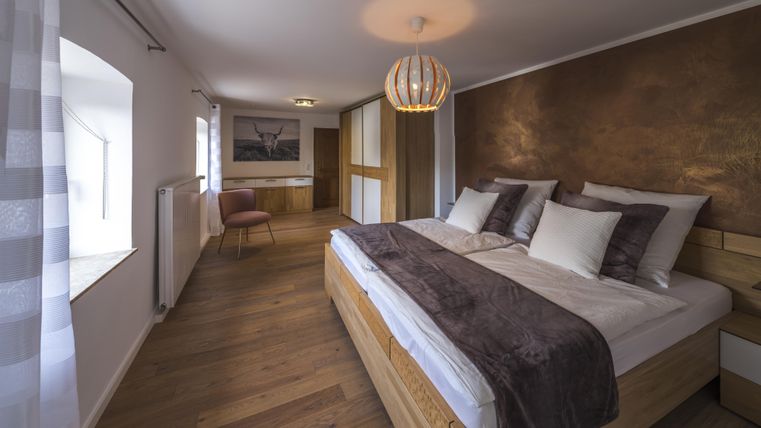 Ein modernes Schlafzimmer mit einem großen Doppelbett und Holzfußboden. Die Wände sind in sanften Farbtönen gehalten und eine Atmosphäre der Ruhe strahlt aus.