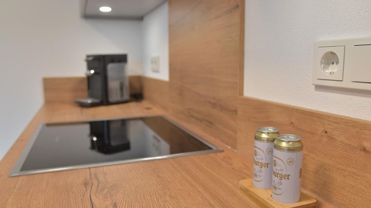 Een moderne keuken met een houten werkblad en een geïntegreerde kookzone. Op de tafel staan twee blikken in een houten standaard.