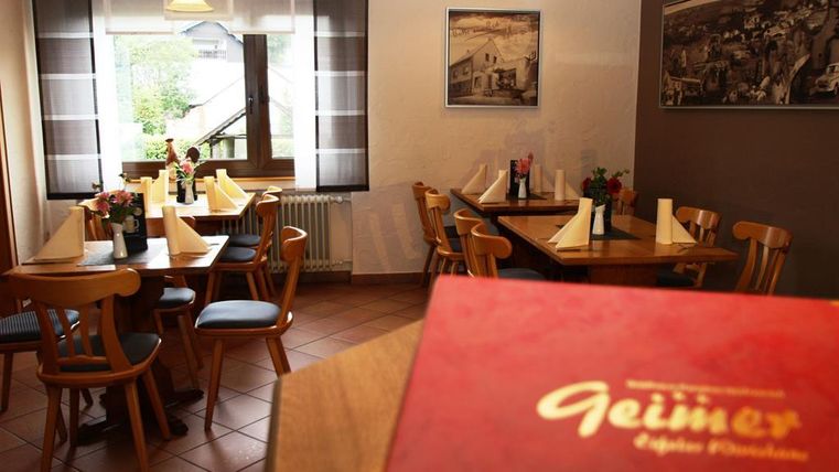 Ein gemütliches Restaurant mit Holztischen und Stühlen. Auf den Tischen stehen Blumen und das Ambiente ist einladend.