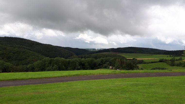 Un paysage verdoyant avec de douces collines et un ciel nuageux. La région semble calme et accueillante.