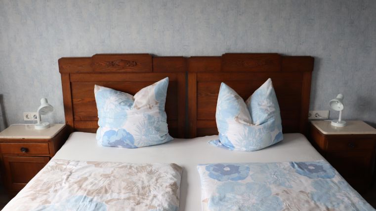 Une chambre confortable avec un grand lit et des coussins décoratifs. Les murs sont peints en bleu clair et le mobilier est en bois sombre.