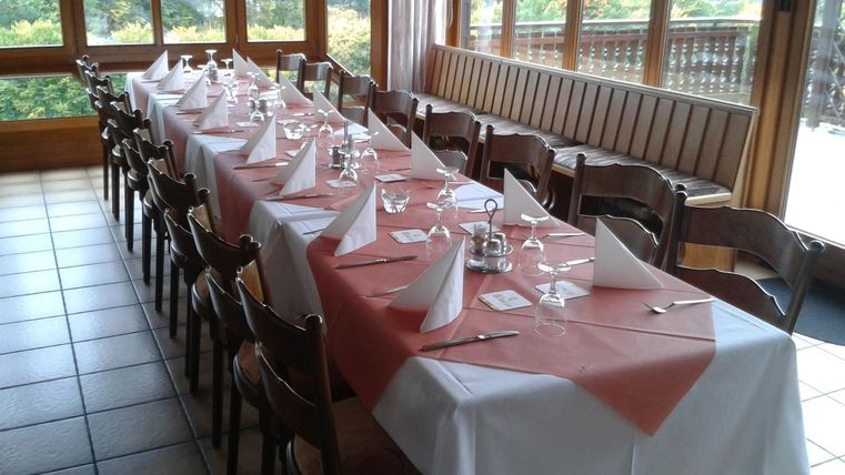 Ein hübsch gedeckter Tisch in einem Restaurant mit Fensterblick. Der Tisch ist mit weißen und roten Tischdecken sowie Geschirr und Gläsern dekoriert.