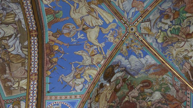 Ein kunstvoll bemalter Deckenbereich mit mythologischen Szenen und lebendigen Farben. Die Darstellung zeigt verschiedene Figuren und Tiere vor einem klaren blauen Hintergrund.