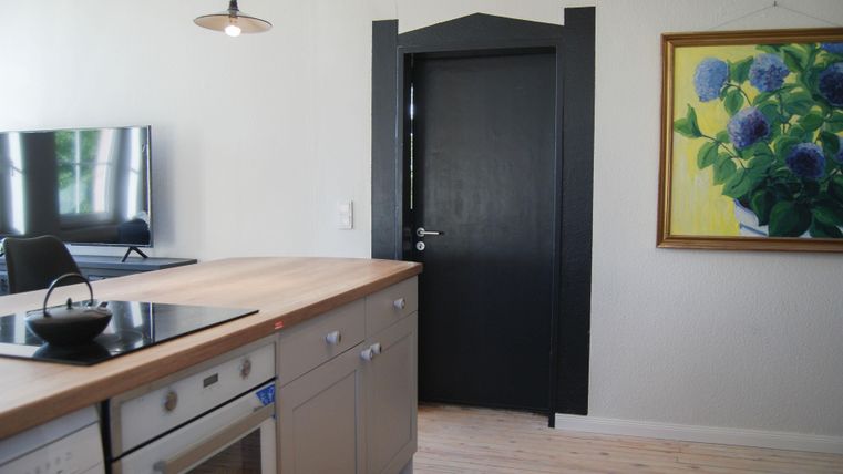 Eine moderne Küche mit einem Holztisch und schwarzen Küchenschränken. An der Wand hängt ein Gemälde von blauen Blumen.