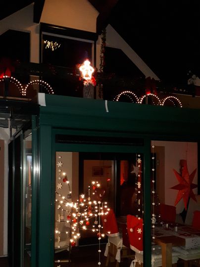 A festively decorated house with lights and Christmas stars. The evening sky creates a cozy atmosphere.