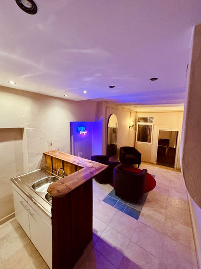 Une vue intérieure moderne avec une petite cuisine et des fauteuils confortables. La lumière crée une atmosphère agréable.