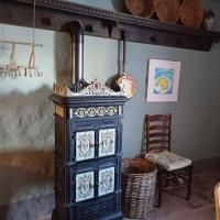 Een traditionele oven staat in een gezellige ruimte. Ernaast zijn een stoel, een mand en enkele decoratieve elementen aan de wand te zien.