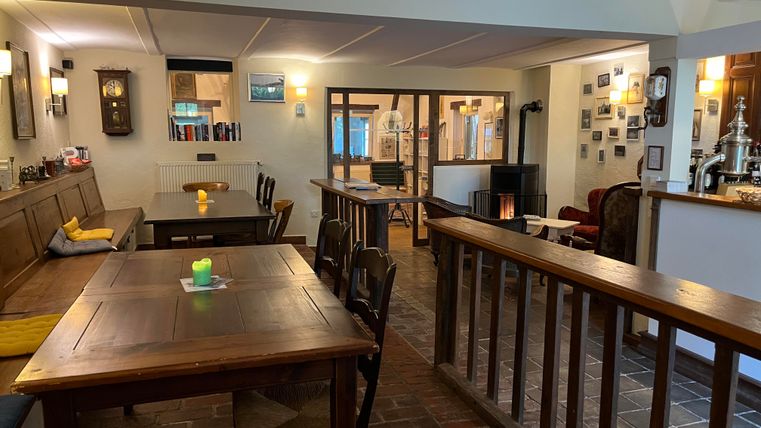 Un établissement cosy avec des tables et des chaises en bois. L'éclairage agréable crée une atmosphère accueillante.