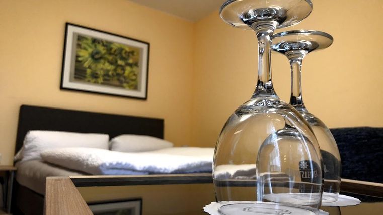 Une chambre d'hôtel confortable avec un lit double et un décor moderne. Sur une table, trois verres à vin créent une atmosphère élégante.
