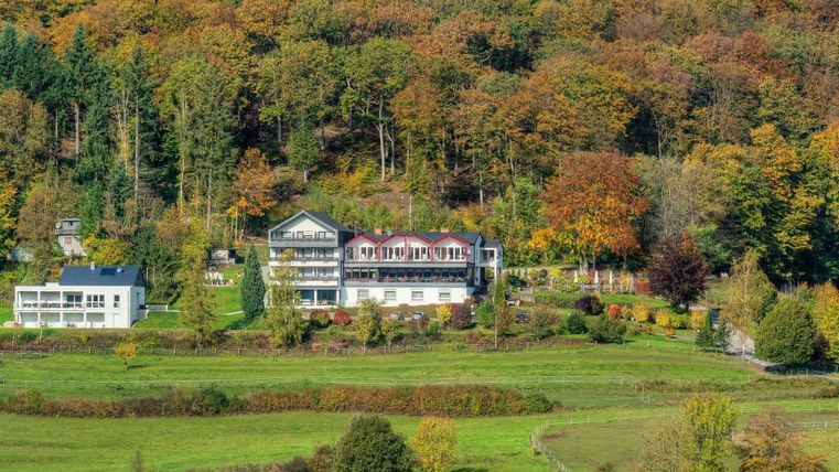 A picturesque hotel surrounded by colorful autumn trees. The green meadow landscape provides a calm and idyllic atmosphere.