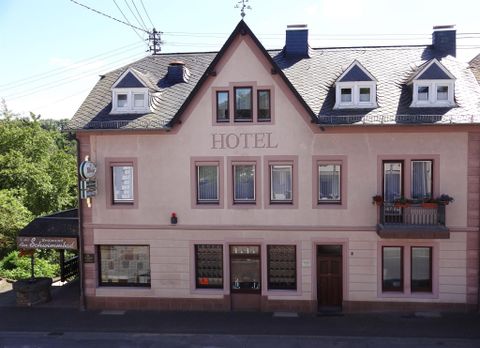 Ein charmantes Hotelgebäude mit mehreren Fenstern. Die Fassade ist in sanften Farben gehalten und hat ein renoviertes Aussehen.