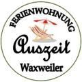 A logo for a holiday apartment named "Auszeit" in Waxweiler. It features a deck chair and a sun umbrella.